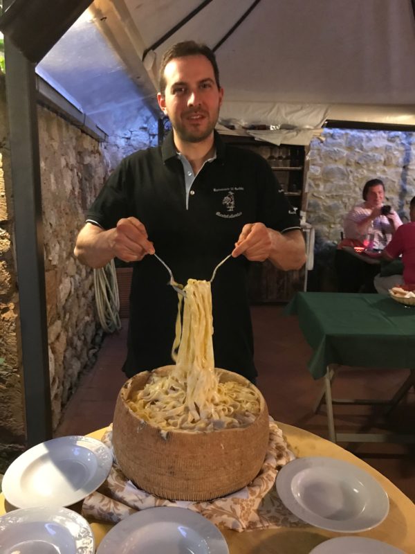 tossing pappardelle in a parmesan wheel at an Italian cooking school