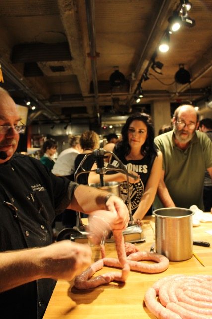 Sheena is turning the crank and Chef is filling the sausage casing.
