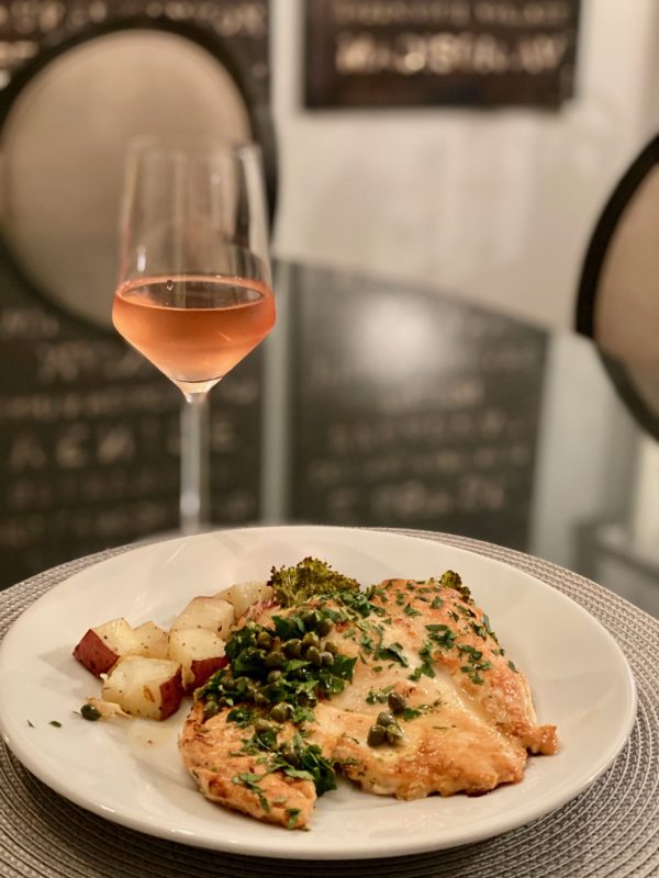 a dish of Chicken Piccata and glass of rosé